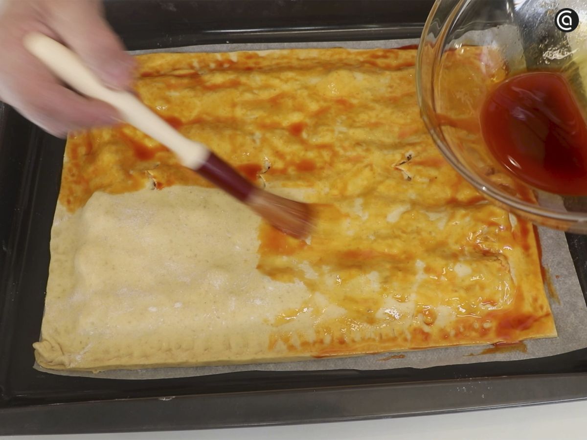 Pincela la empanada con el caldito del sofrito