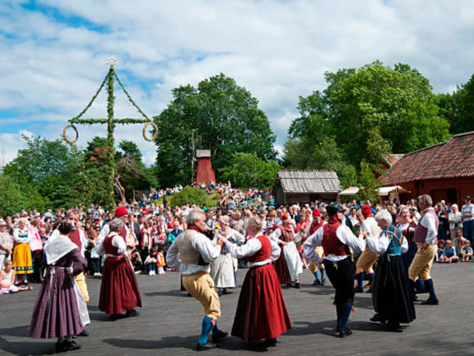 La gente baila alrededor del midsommarstången (una rama decorada)