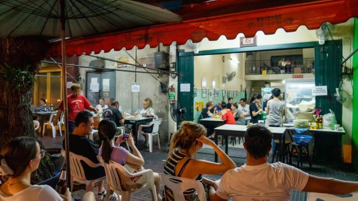 Varias personas esperan su turno para comer en el puesto de comida callejera Jay Fai, de Bangkok