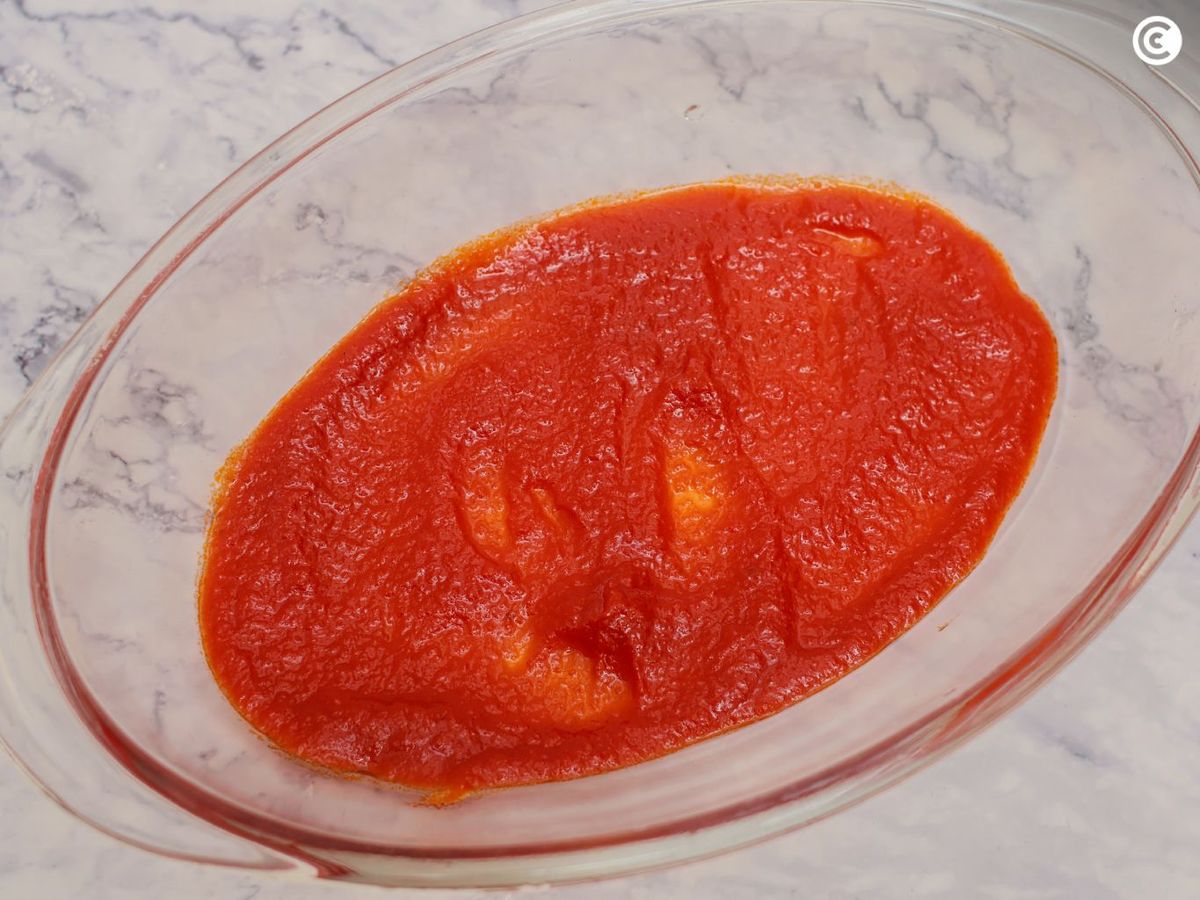 Cubrir la base de la fuenta del tian de verduras con salsa de tomate