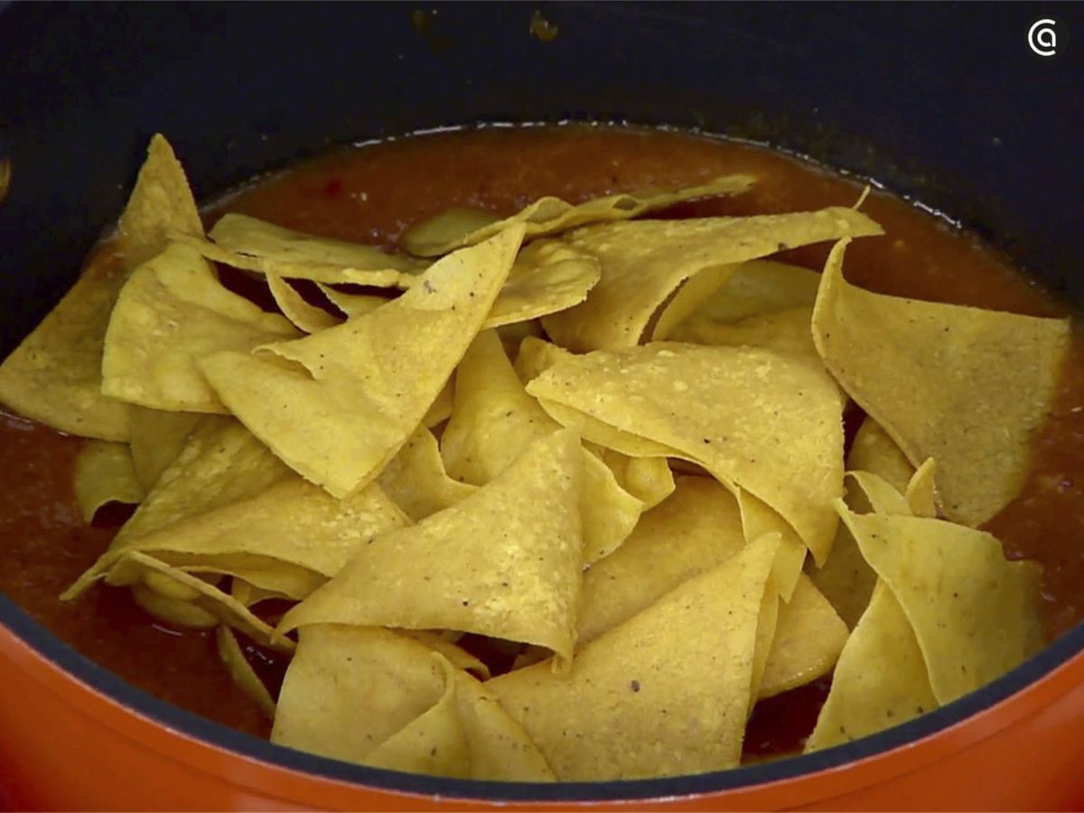 Remoja los totopos en la salsa roja