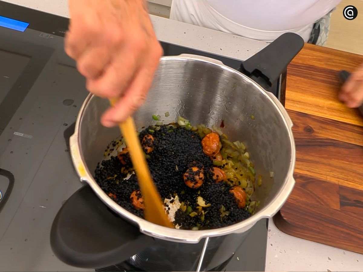 Agrega chorizo y lentejas, cubre con agua y cocina en la olla rápida