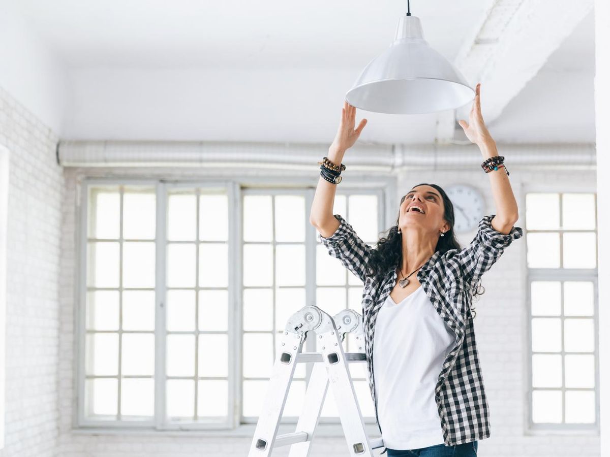 ujer colocando una lámpara de techo.