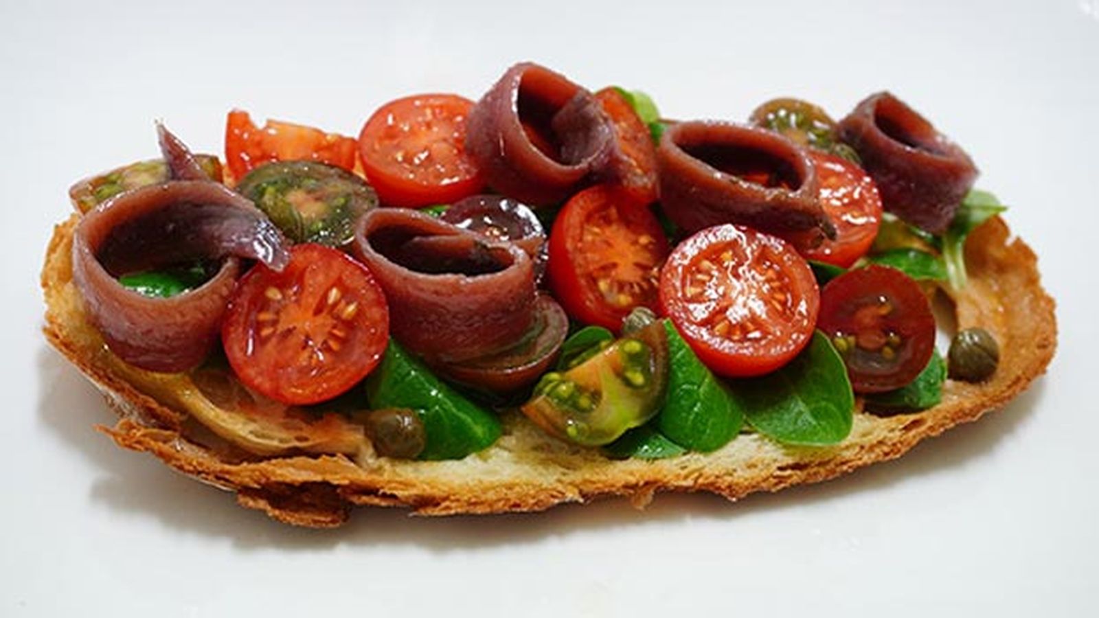 Tosta de anchoas con tomate y canónigos Tosta de anchoas con tomate y canónigos