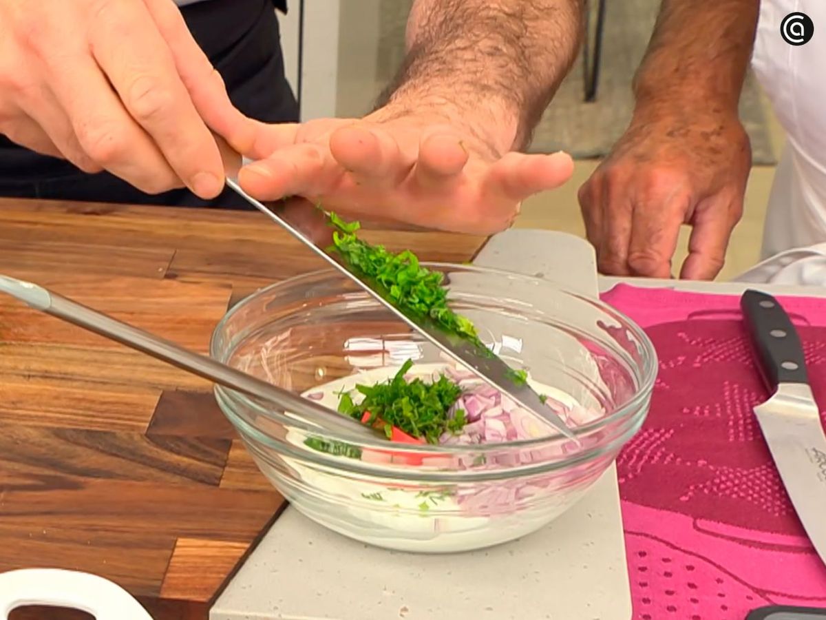 Añade las hierbas picadas al bol y mezcla con el yogur, la mostaza y la cebolla