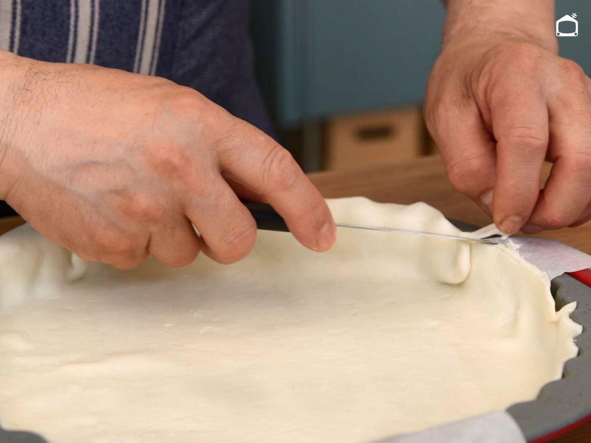 Corta el sobrante de la masa en el molde para el quiche de jamón y queso