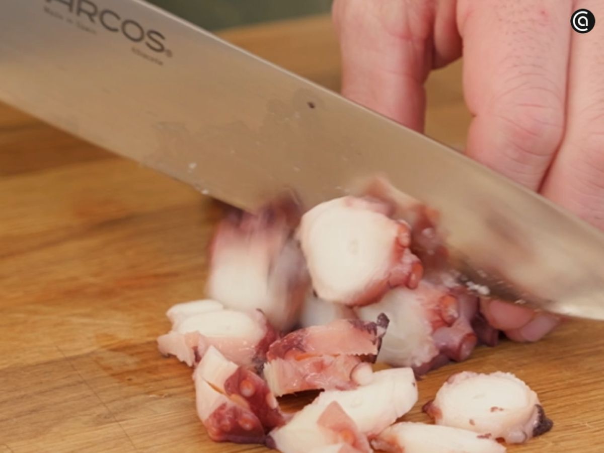 El pulpo cocido se corta en dados pequeños para integrarlo en la mezcla.