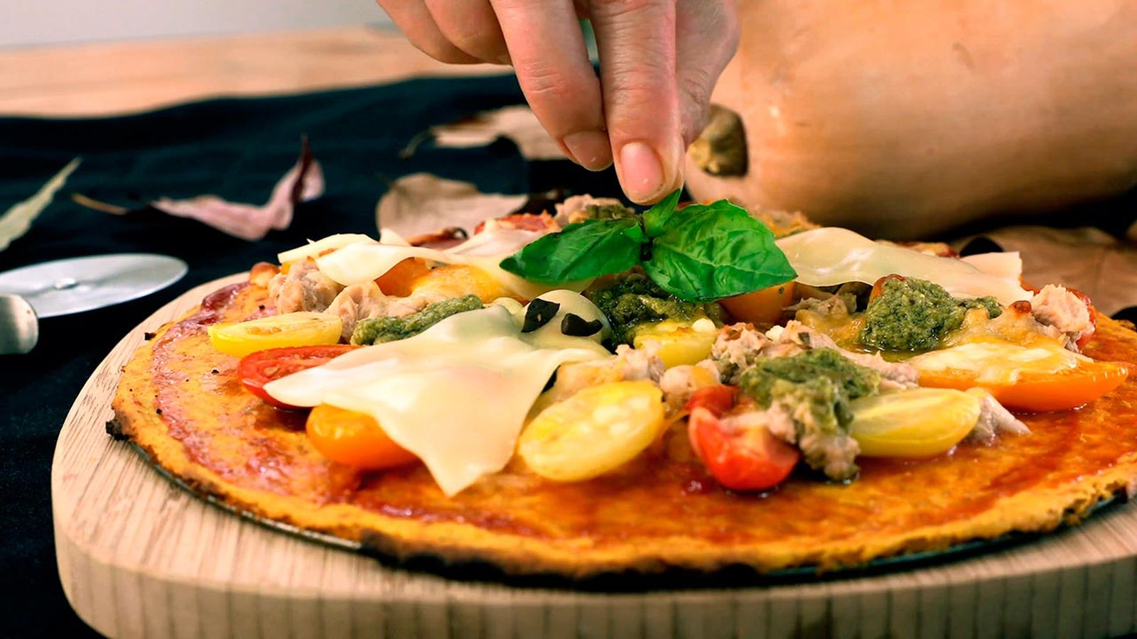 Sirve la pizza templada y decora con una hoja de albahaca Receta de pizza fantasma para Halloween paso 5
