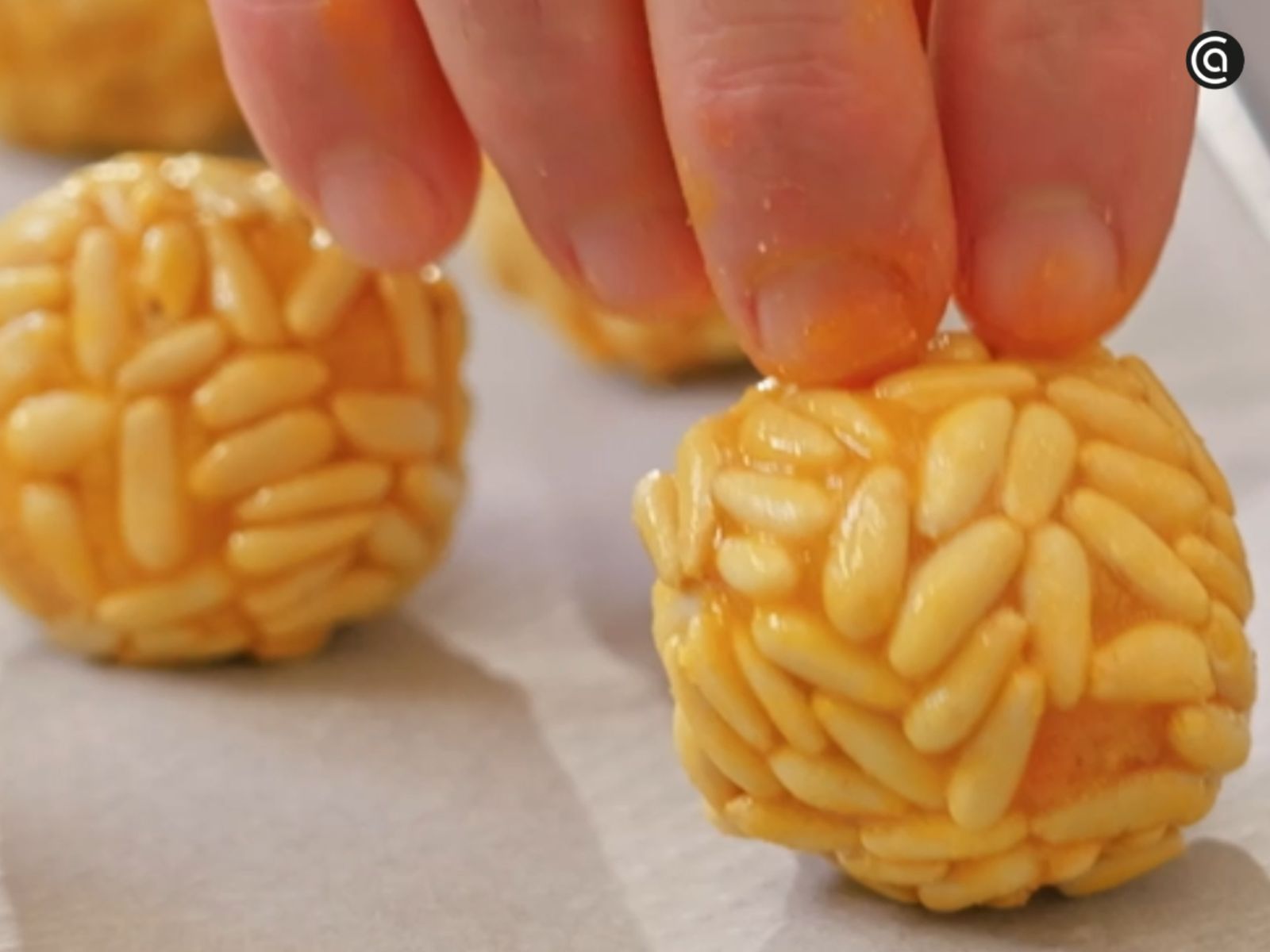 Cada bolita se reboza con piñones, presionándolos ligeramente para que se adhieran bien. Cada bolita se reboza con piñones, presionándolos ligeramente para que se adhieran bien.
