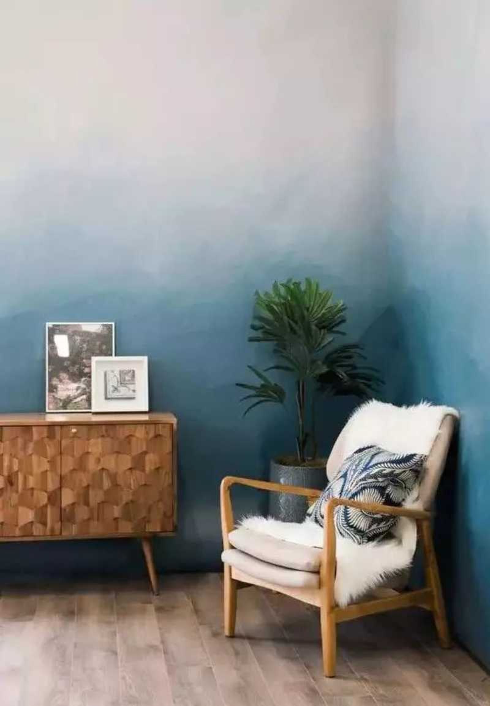 Rincón del salón con pared de efecto ombré en tonos azules verdosos.