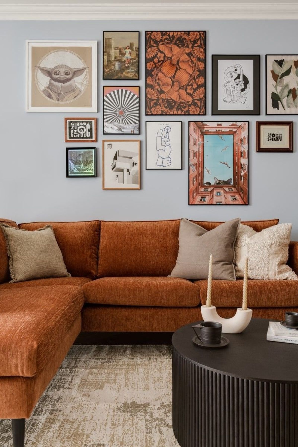 Salón moderno con ilustraciones, sofá naranja y muebles oscuros.