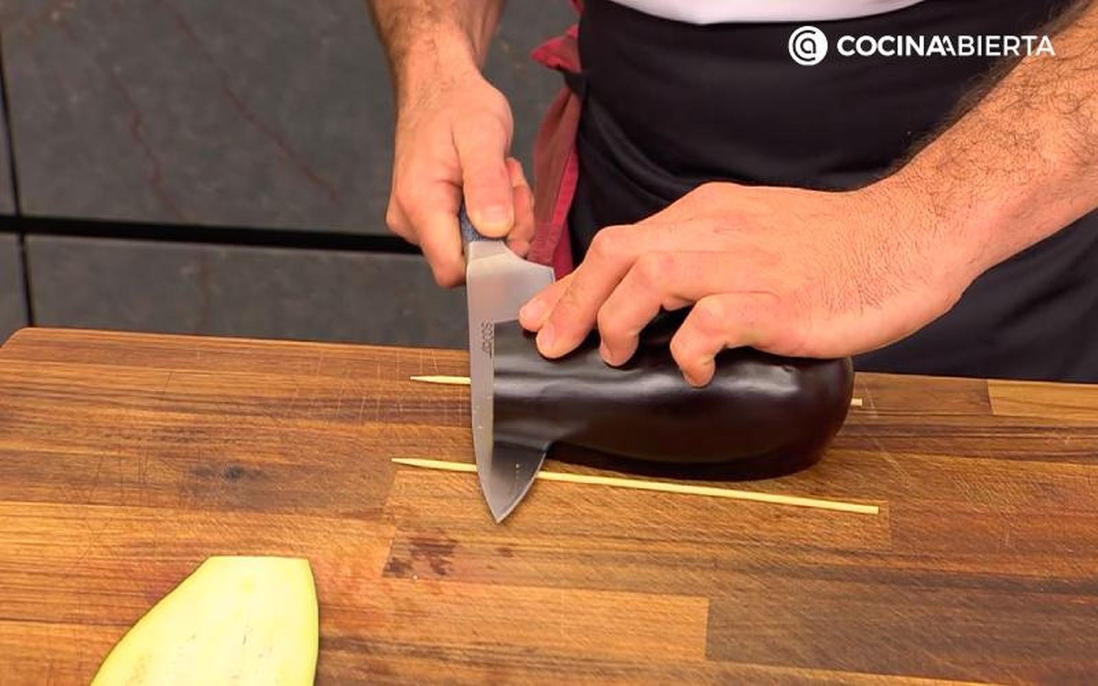Desliza el cuchillo al nivel de los palillos, cortando la berenjena Desliza el cuchillo al nivel de los palillos, cortando la berenjena