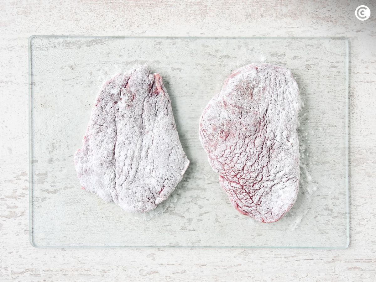 Enharinar los filetes de ternera para hacerlos empanados