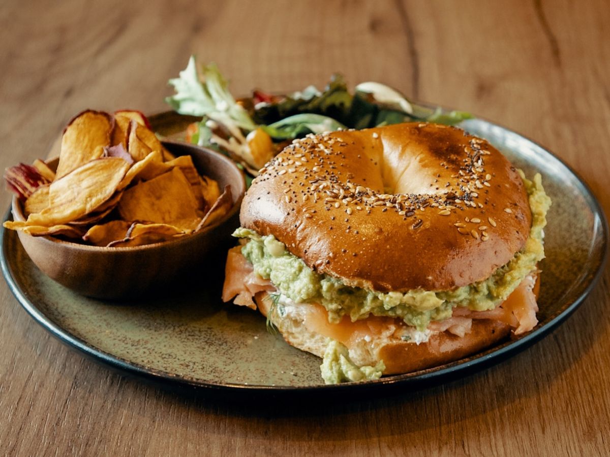 Bagel de salmón y guacamole con chips caseros y ensalada, una opción de brunch en Mokambo Sevilla.