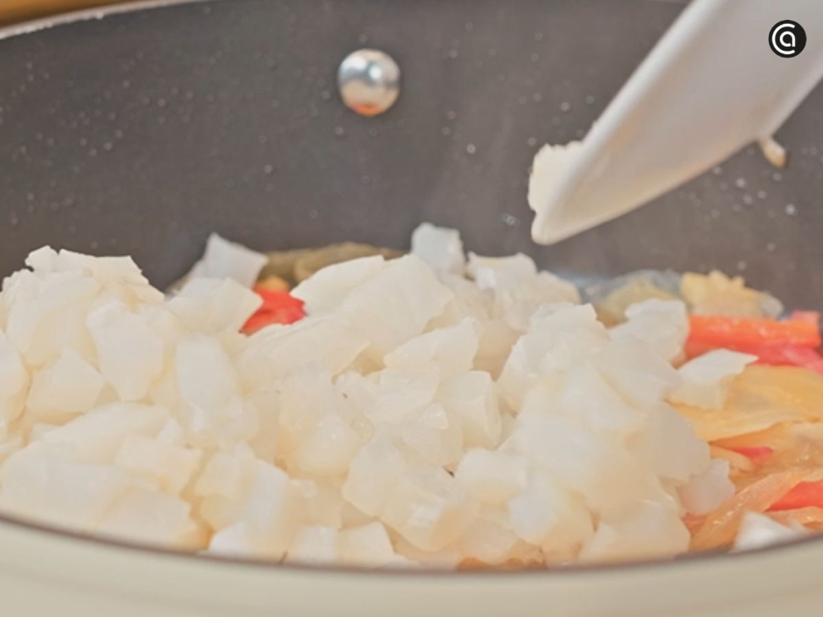 Incorpora el bacalao troceado al sofrito y mézclalo con cuidado para que se impregne bien del aceite y las verduras.