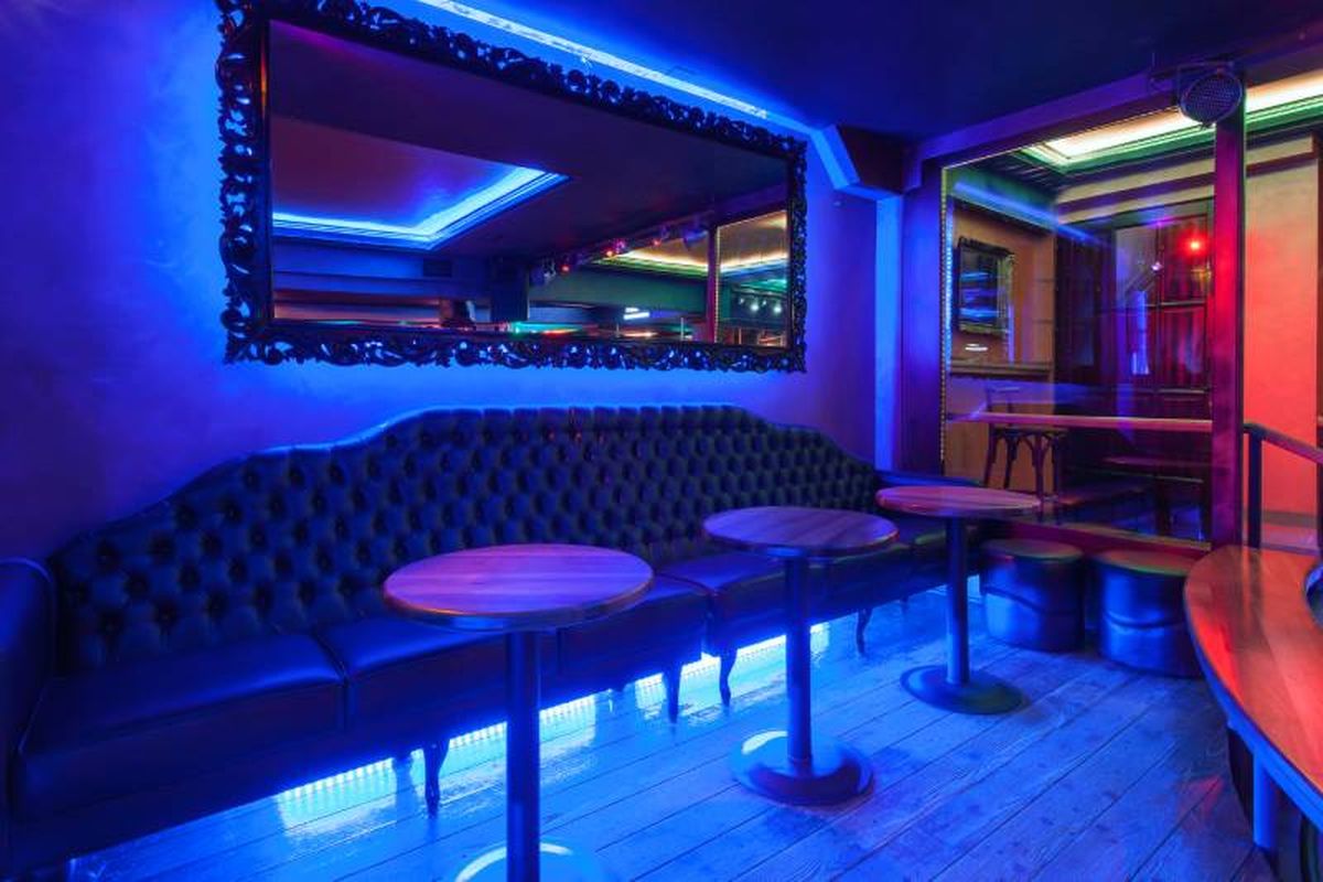 Discoteca pequeña con luces de neón y espejo barroco.