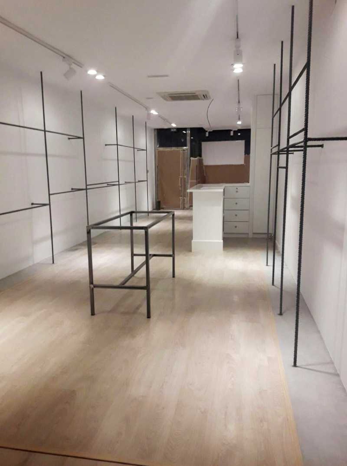 Estanterías de ferralla mesa industrial y laterales con suelo de cemento pulido.