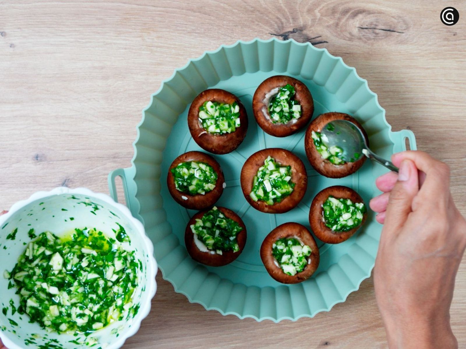 Distribuye el majado de ajo y perejil sobre el interior de los champiñones