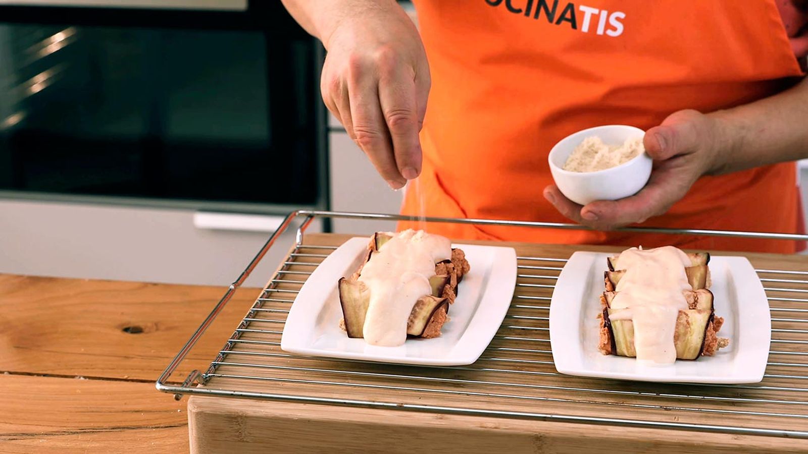 Monta los canelones, añade la bechamel por encima y espolvorea un poco de queso Receta de canelones veganos de berenjena, calabaza y setas paso 6