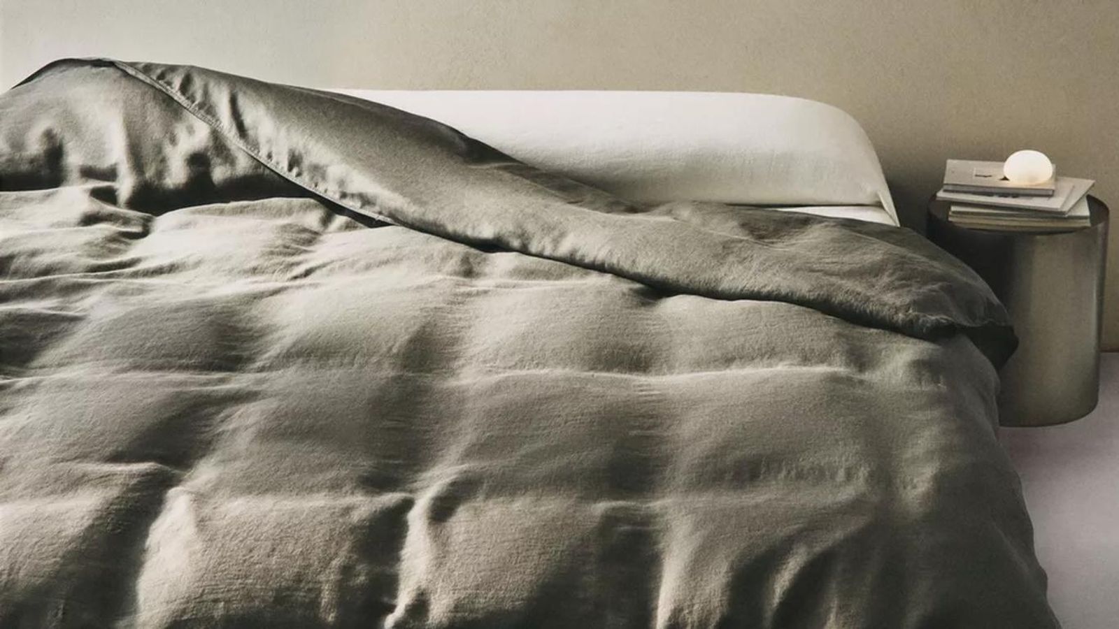 Dormitorio con lámpara de alabastro redonda de Zara Home.