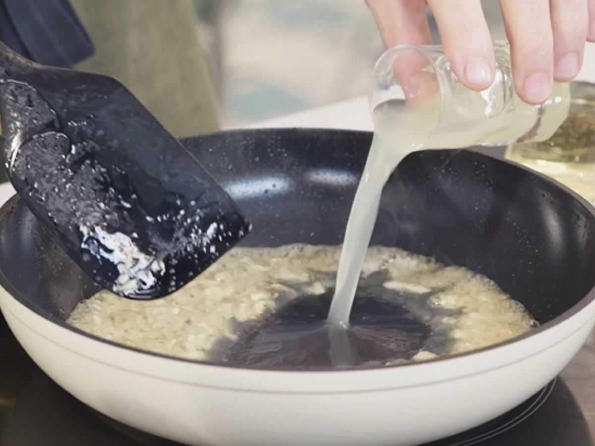 Añade el zumo de limón y el vino blanco al sofrito de ajos para crear una salsa ligera y aromática.