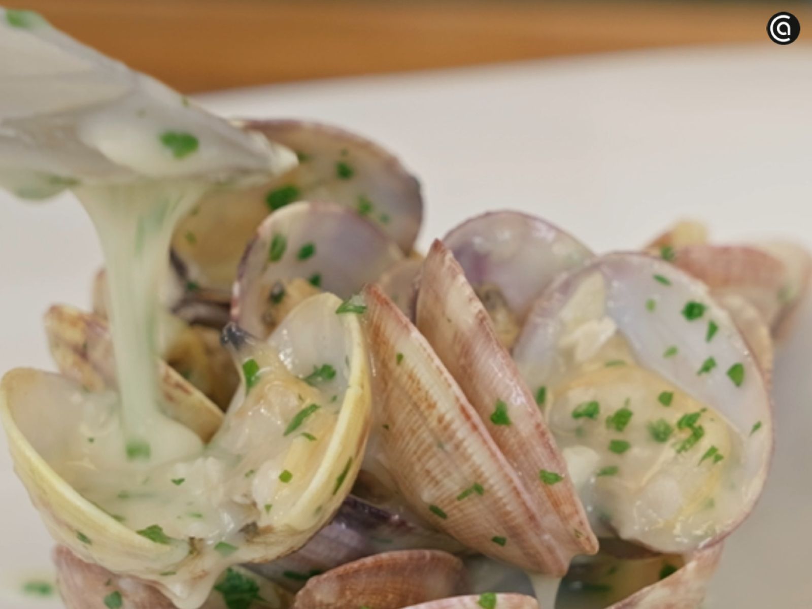 Las almejas se sirven calientes con la salsa verde recién hecha vertida por encima.