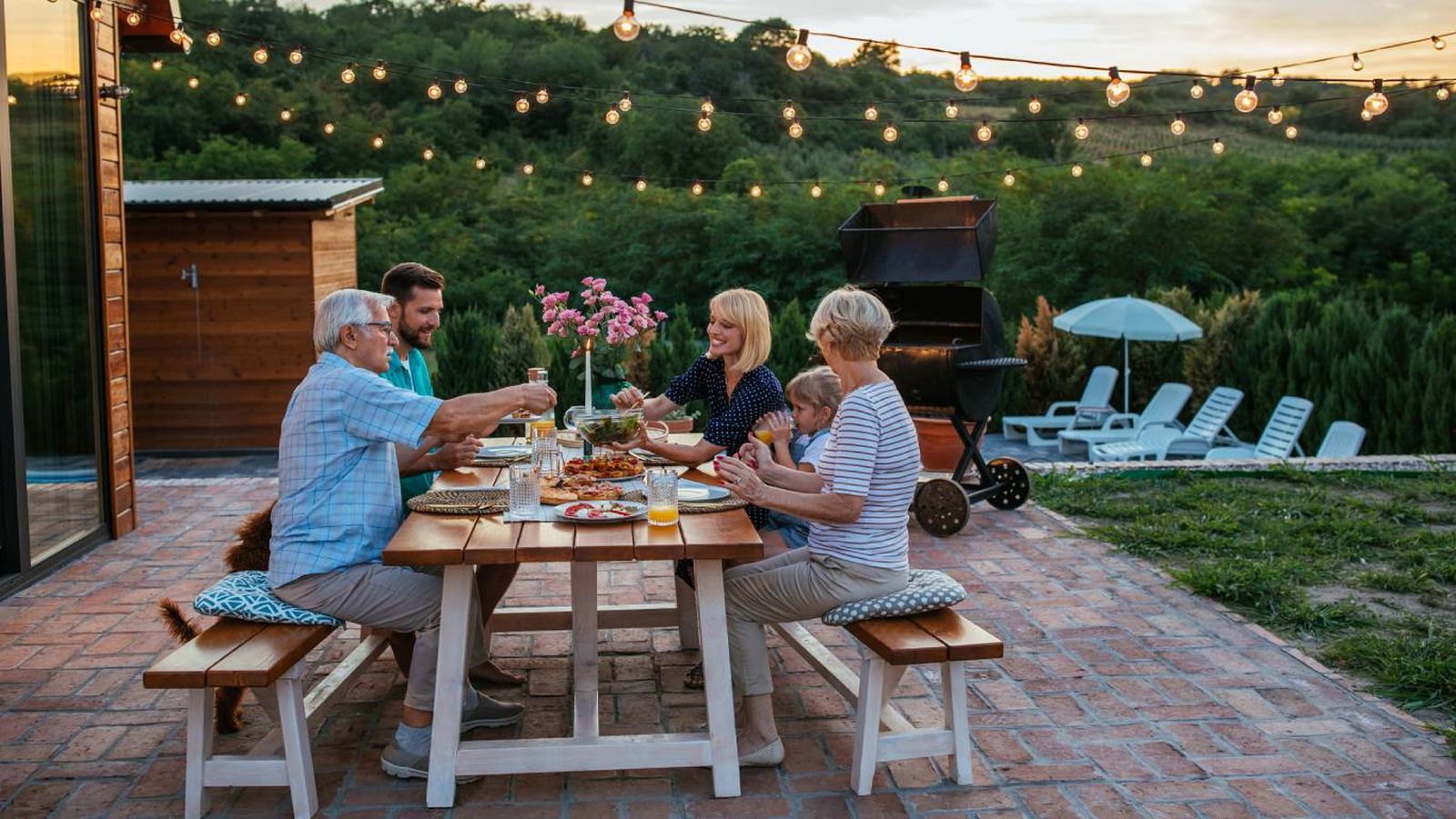 Familia comiendo en un jardín con muebles atemporales.