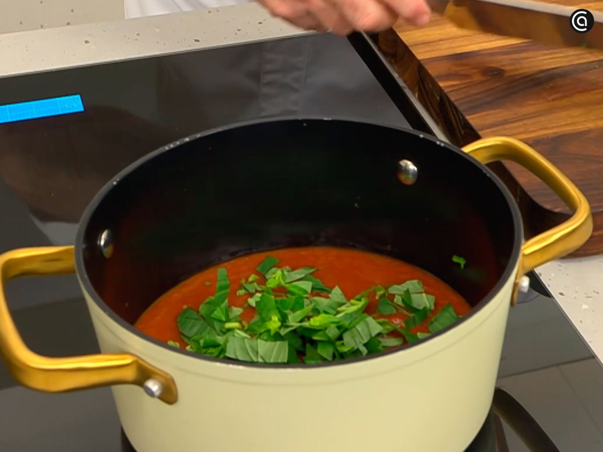 Pon la salsa de tomate al fuego y mézclala con albahaca picada