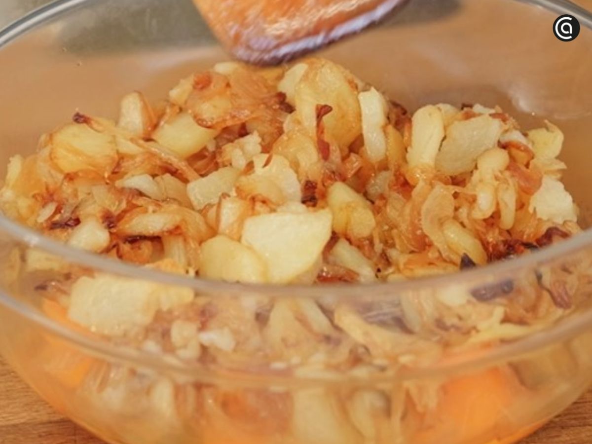 Una vez tiernas y ligeramente doradas, las patatas y la cebolla se escurren y se mezclan con el huevo.