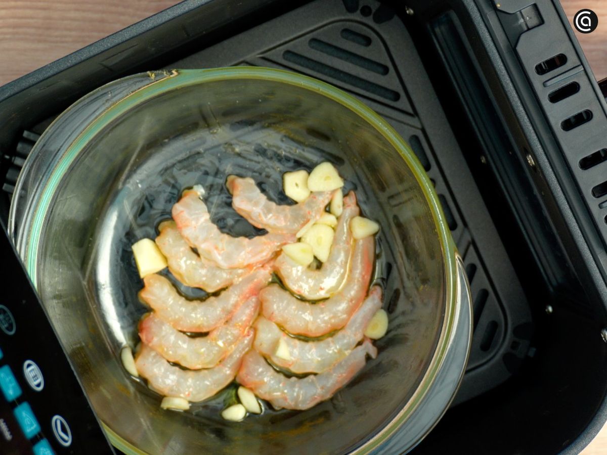 Pon las gambas, las láminas de ajo con un poco de aceite en la freidora de aire y cocínalas