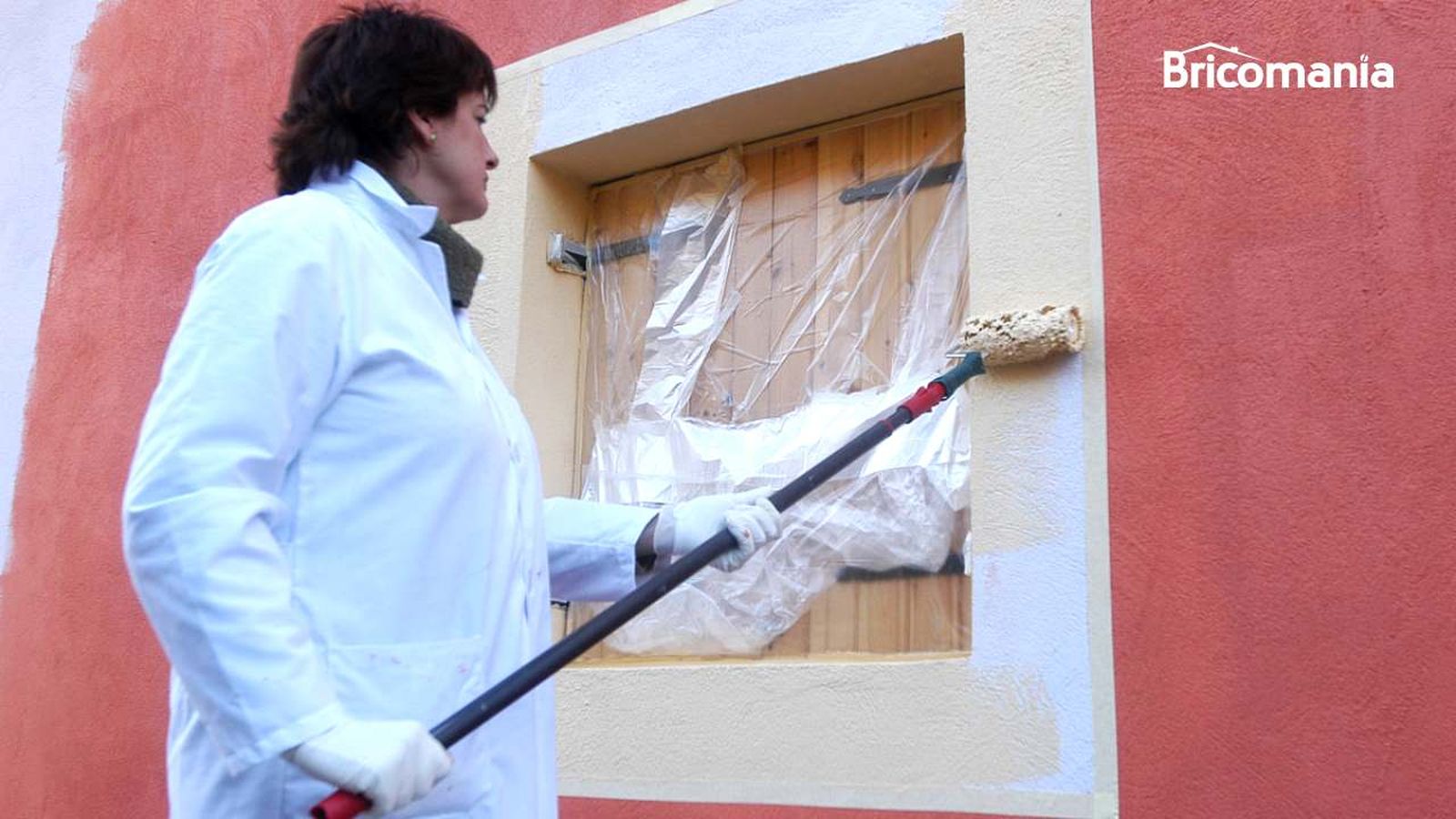 Persona pintando una pared de la fachada Persona pintando una pared de la fachada
