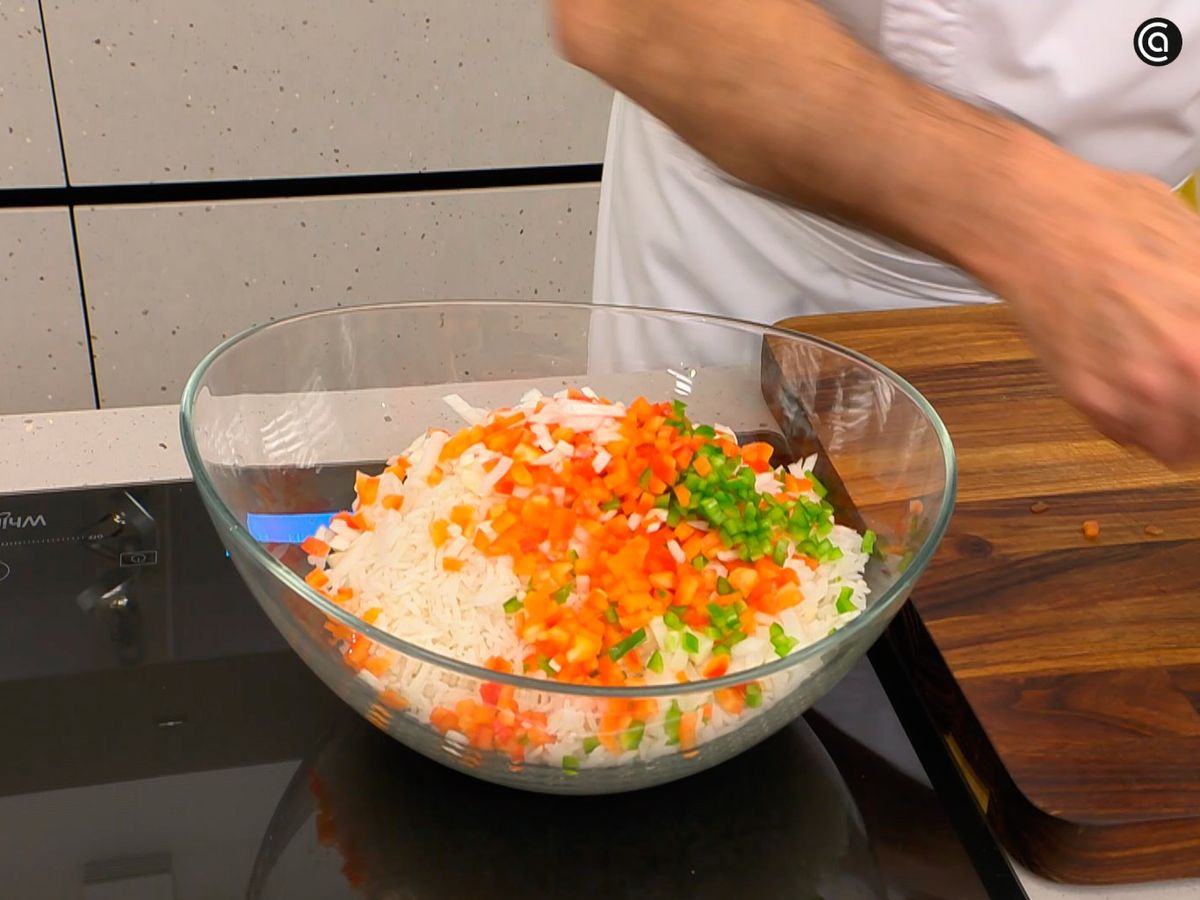 Pica la cebolleta y los pimientos y añádelos al bol junto con el arroz