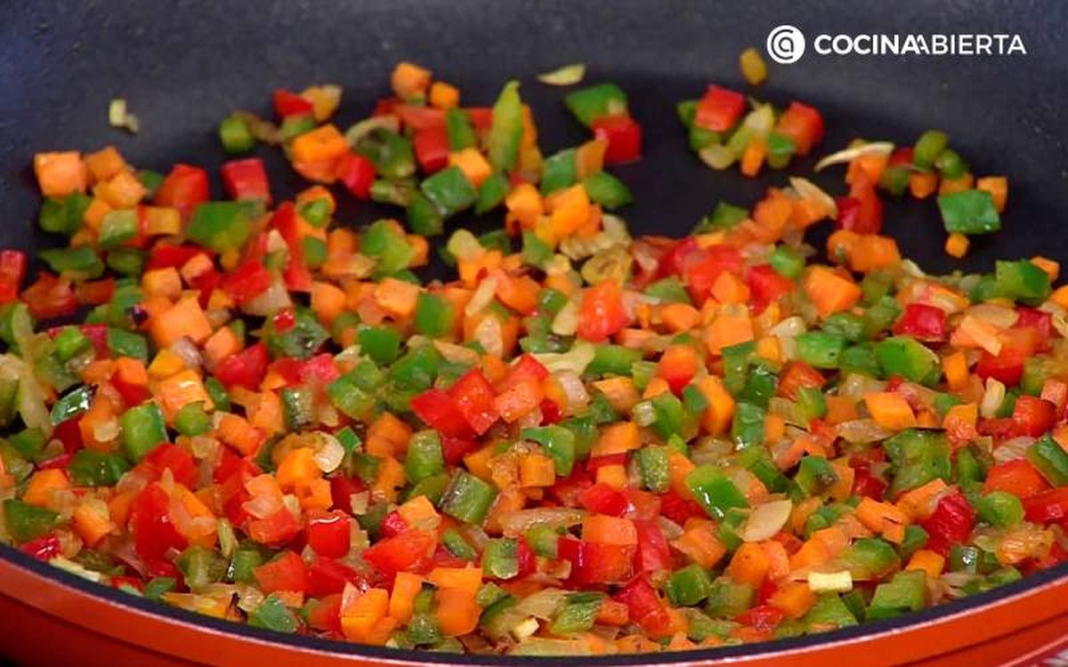 Saltea la cebolleta, la zanahoria y los pimientos en una sartén