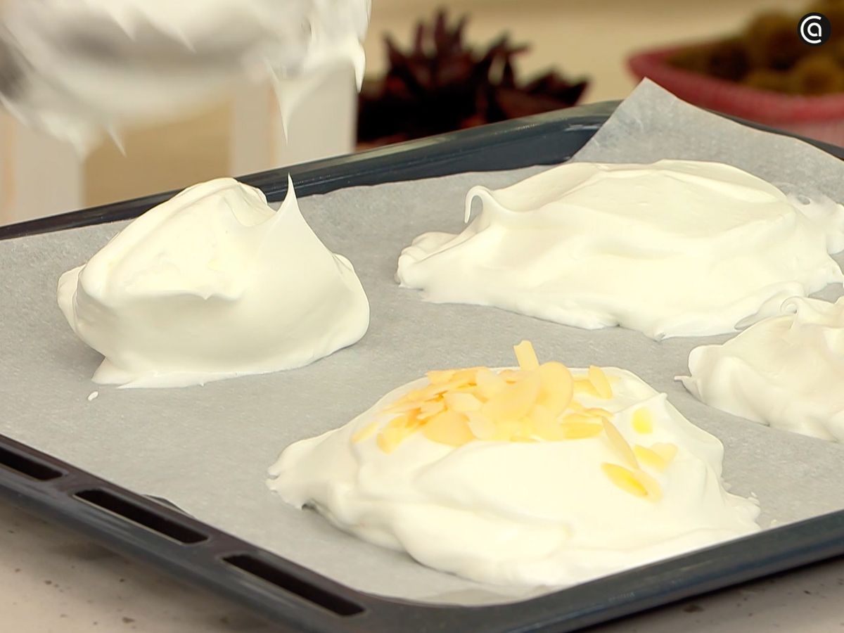 Forma cuatro montañitas de merengue sobre la bandeja, cúbrelas con almendras y hornéalas
