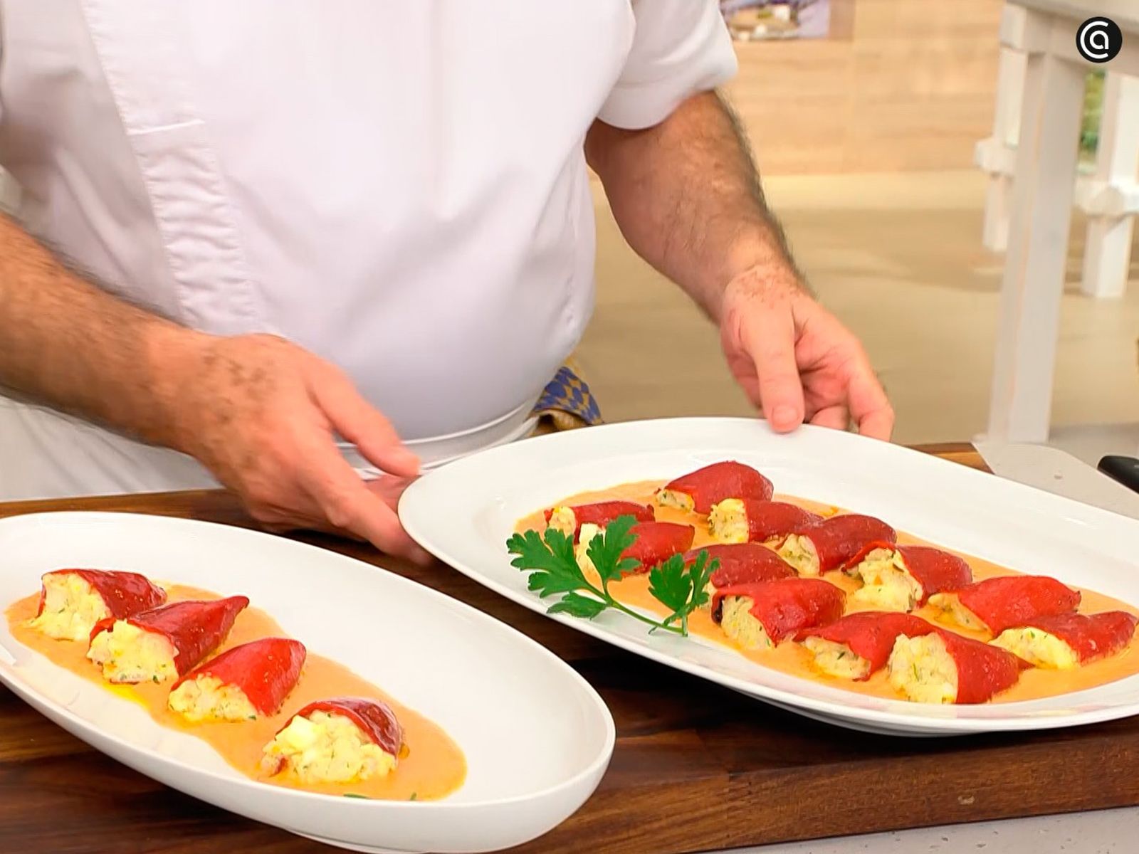 Coloca los pimientos rellenos de merluza y huevo encima de la salsa