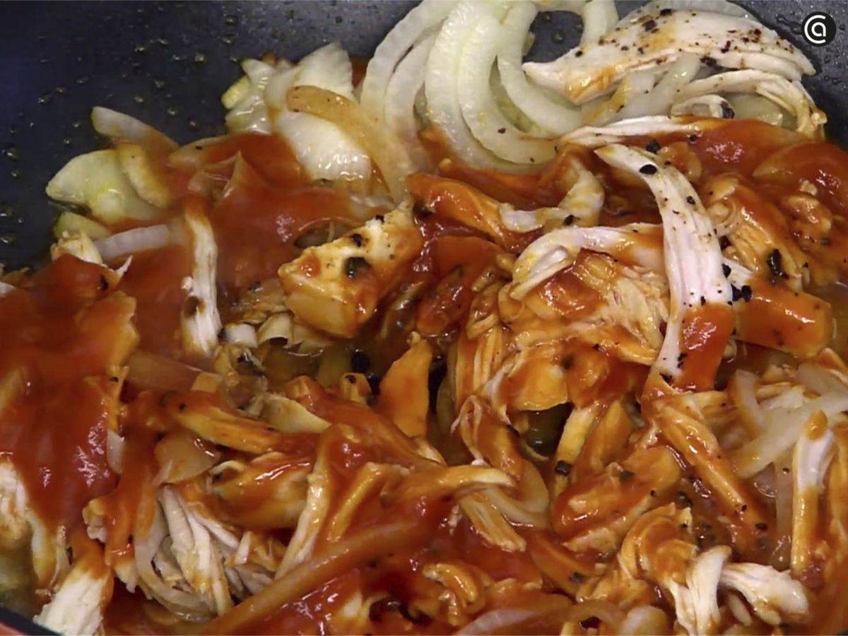 Agrega el pollo y la salsa de tomate a la sartén junto con la cebolla y el ajo