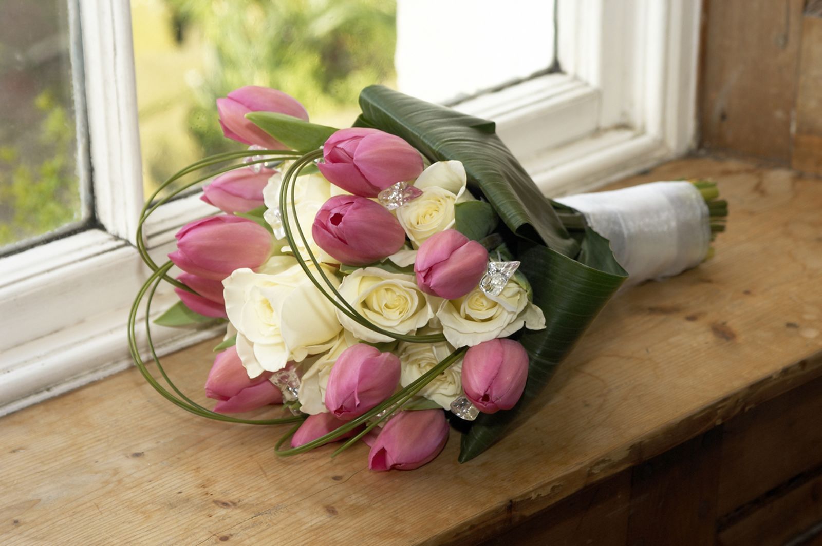 Ramo de tulipanes rosas y blancos en ventana