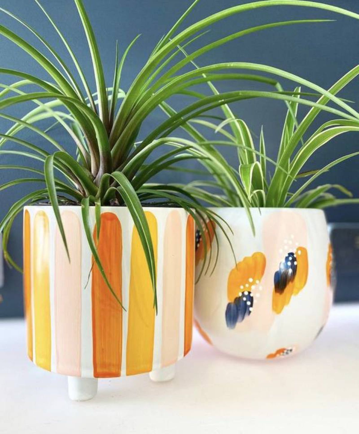 Macetas pintadas a pinceladas en naranja y azul.