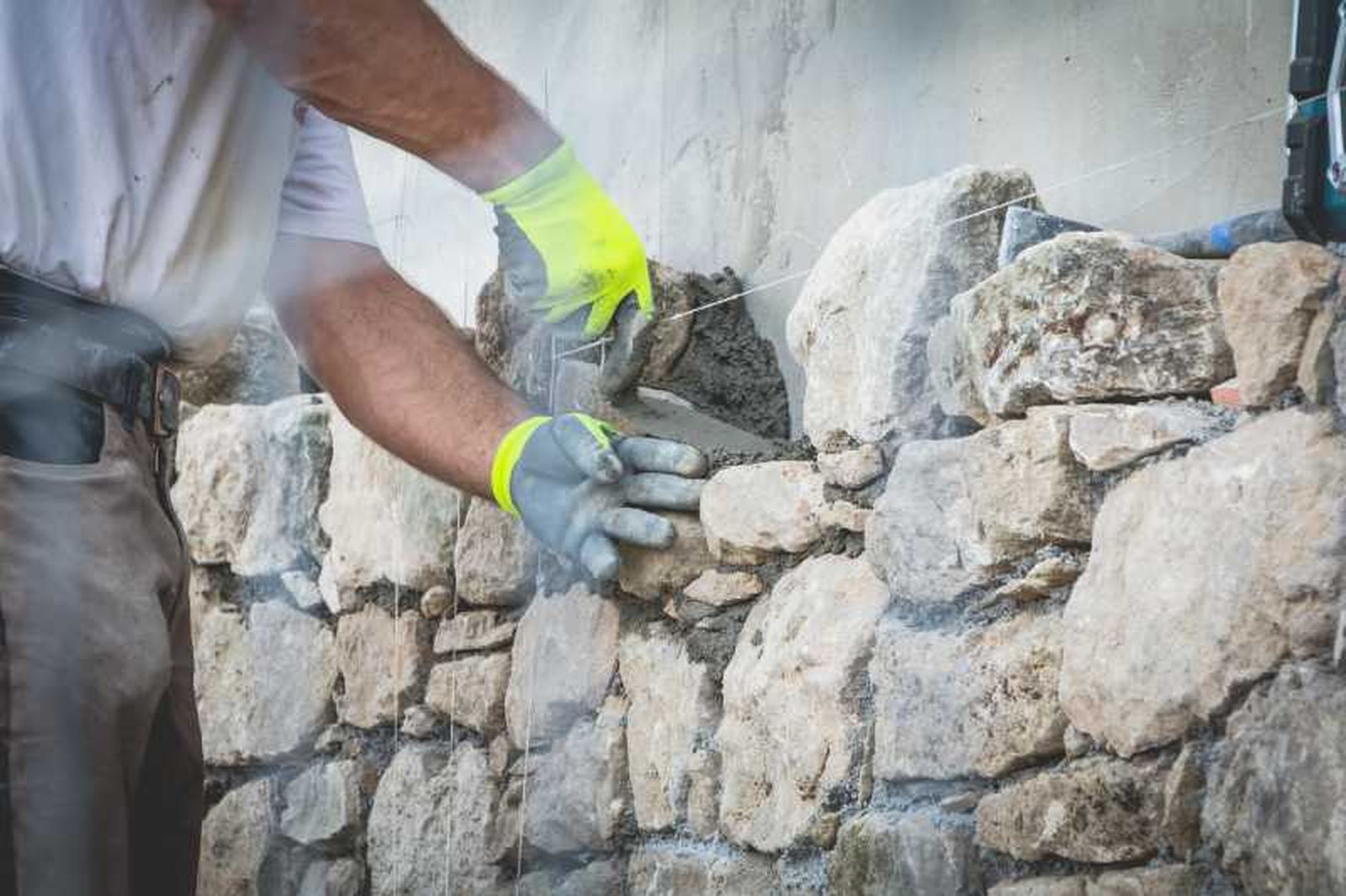 Profesional haciendo una pared de piedra.