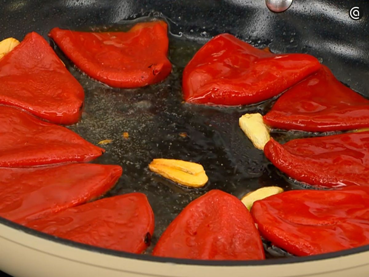 Dora el ajo en láminas y añade los pimientos para cocinarlos