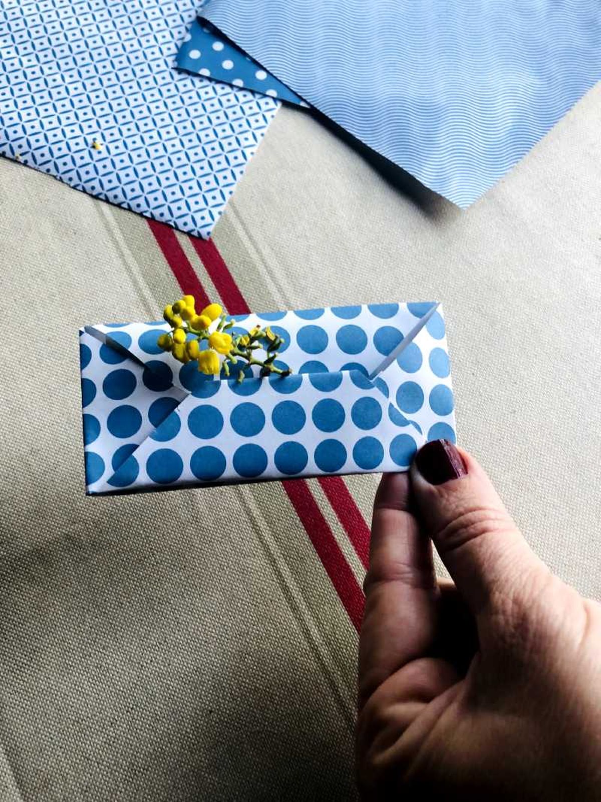 Sobre de papel geométrico decorado con una flor amarilla.