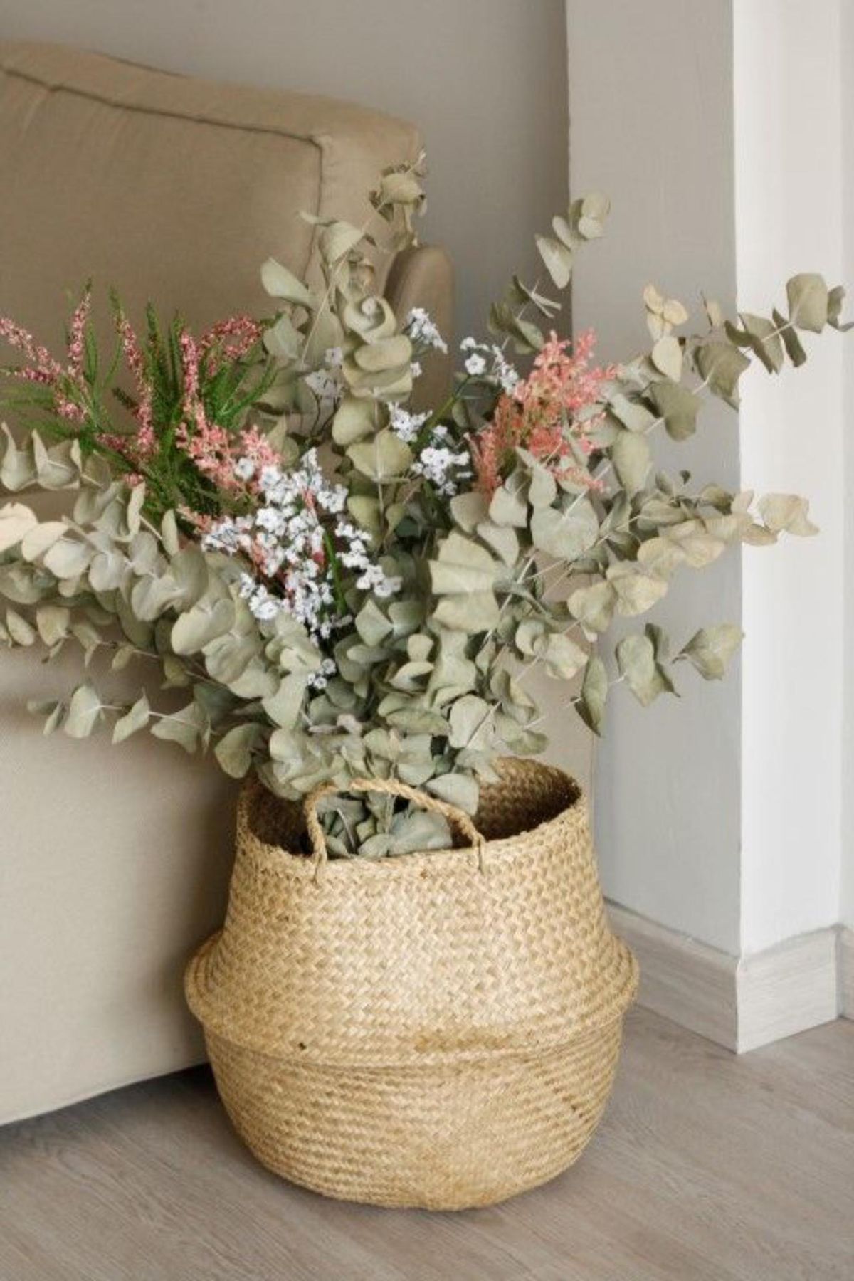 Cesta de mimbre con flores al lado del sofá del salón.