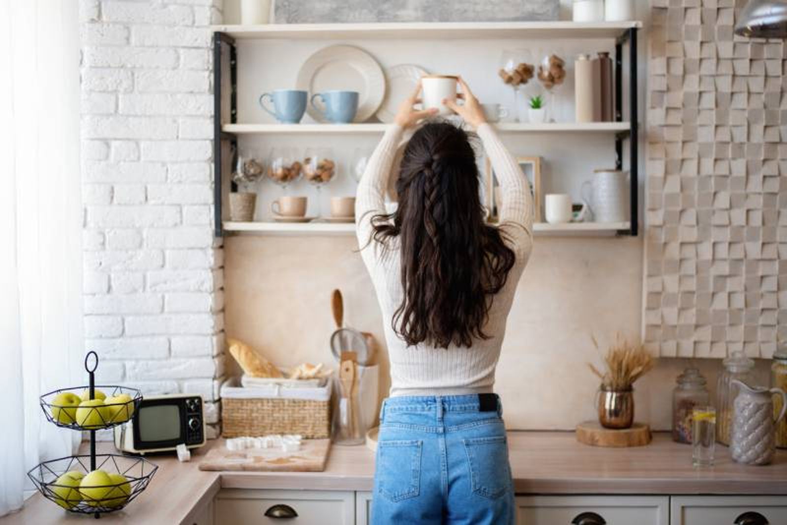 Mujer organizando la estantería de la cocina. Mujer organizando la estantería de la cocina.