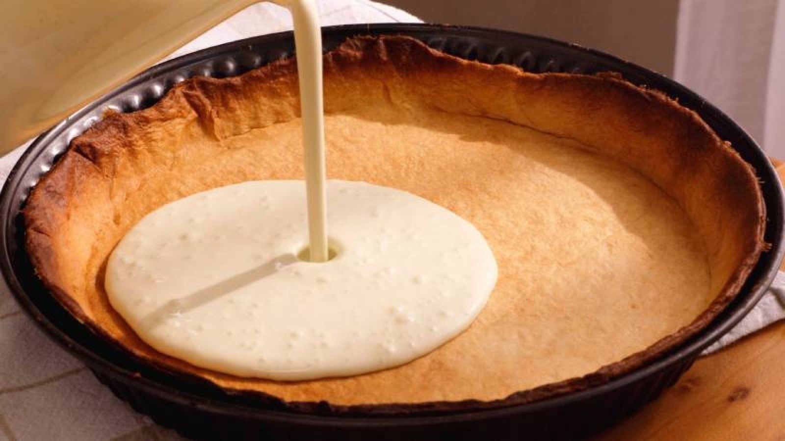 Vierte la nata sobre la base de galleta para crear la cremosidad perfecta en tu tarta de queso Vierte la nata sobre la base de galleta para crear la cremosidad perfecta en tu tarta de queso