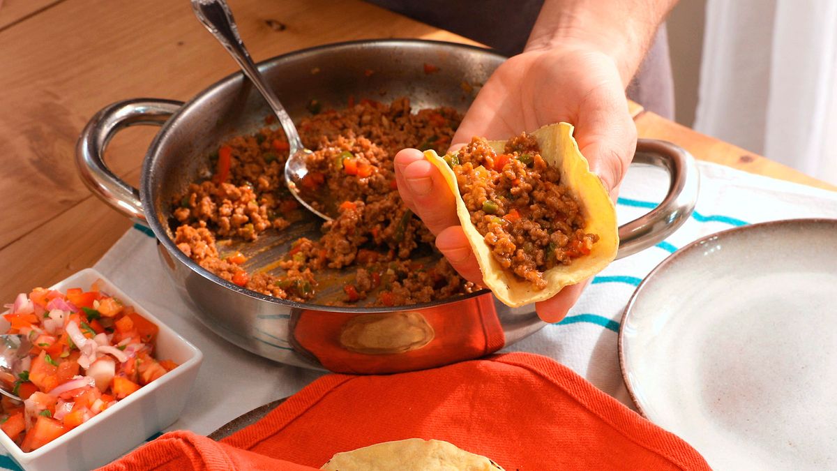 Sirve las tortillas de maíz dobladas, rellenas de carne picada y cubiertas con fresco pico de gallo
