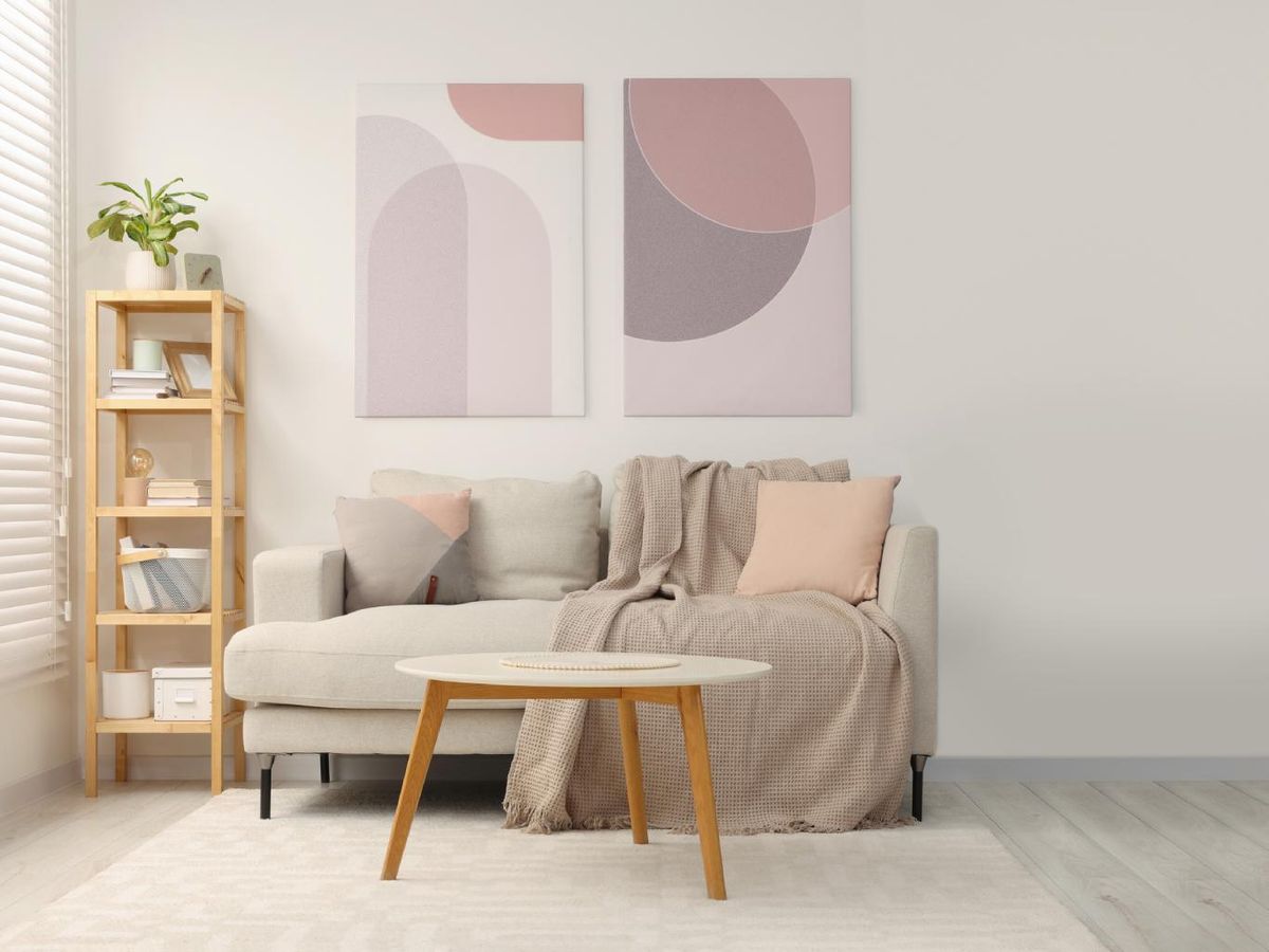 Sofá beige de un estudio con cuadros minimalistas lavanda.