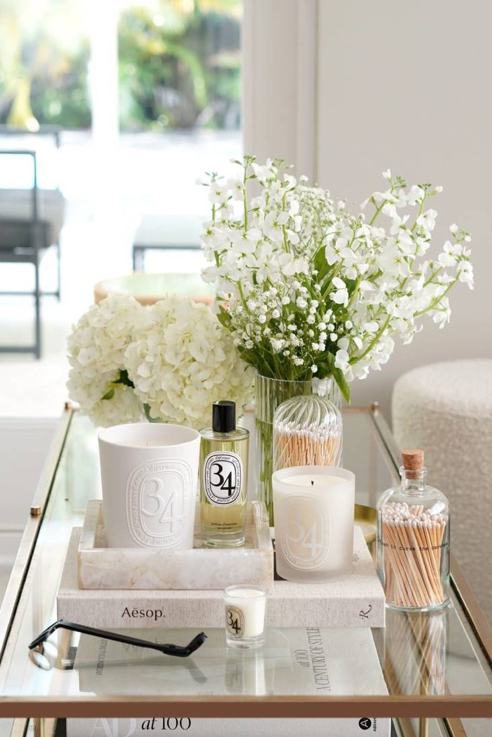 Mesa de centro con flores y complementos en tonos blancos.