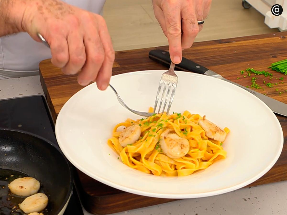 Espolvorea cebollino picado sobre los tallarines con vieiras