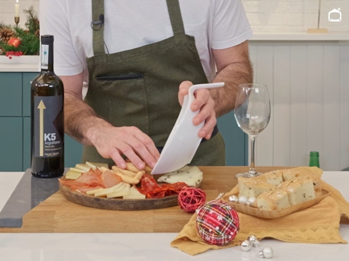 La tabla va tomando forma con queso, embutidos y pan colocados con orden.