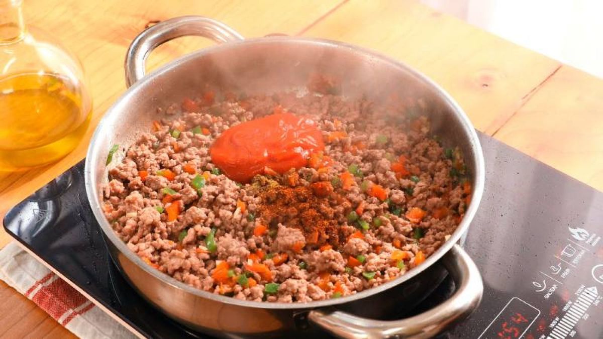 Añade comino, chile y salsa de tomate a la mezcla y remueve bien para combinar los sabores